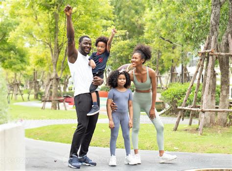 Happy family exercise in natural park. Black skin family, husband and wife have fun, laughing ...