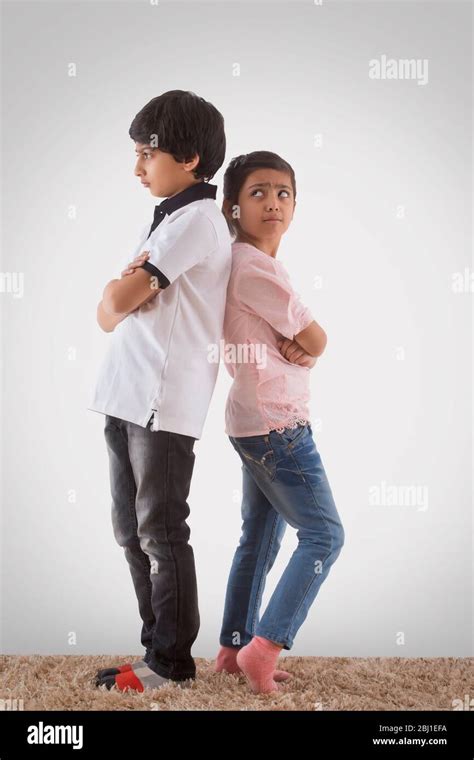 brother and sister standing back to back after fight Stock Photo - Alamy