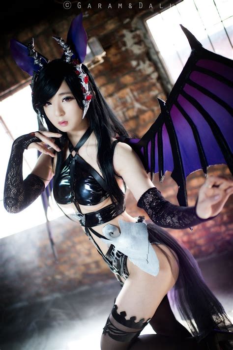 a woman dressed up as a demon with wings on her head and gloves, posing for the camera