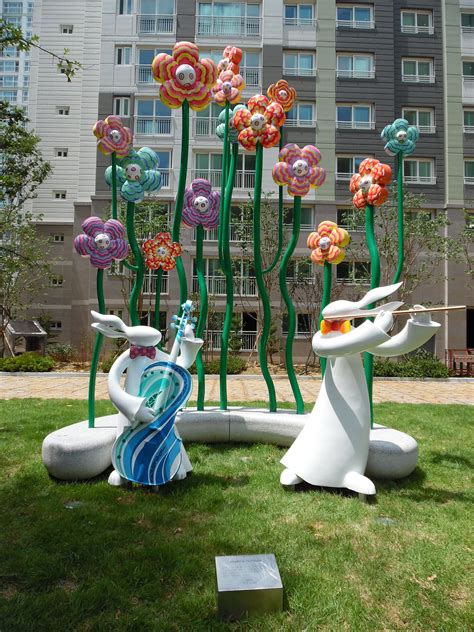 two sculptures in the grass with flowers on them