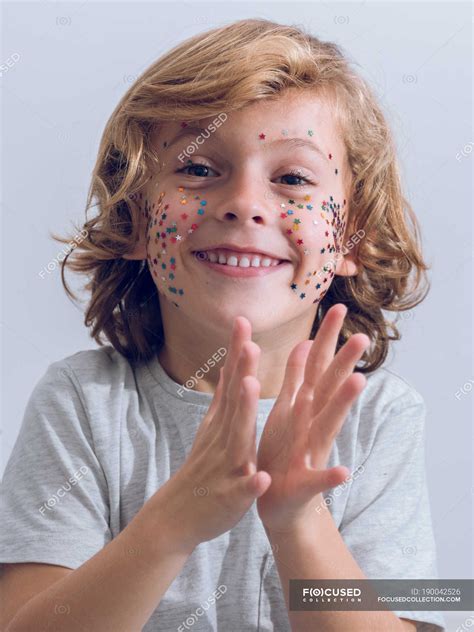 Cheerful boy with confetti on face clapping hands — childhood, applause - Stock Photo | #190042526