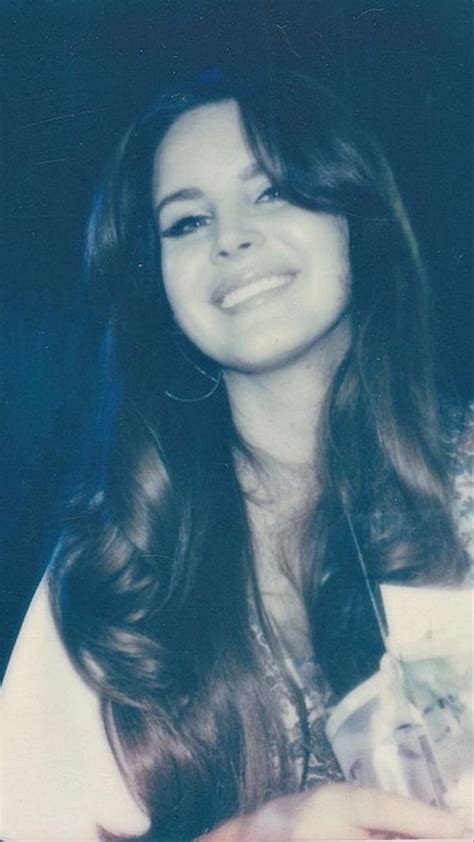 a woman with long brown hair smiling and holding something in her hand ...