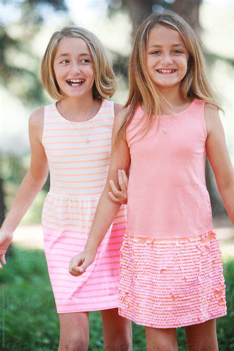 Happy Fraternal Twin Sisters Wearing Dresses Laughing | Stocksy United