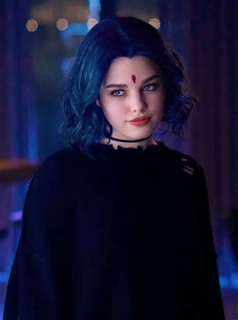 a woman with blue hair wearing a black shirt and choker in a dark room