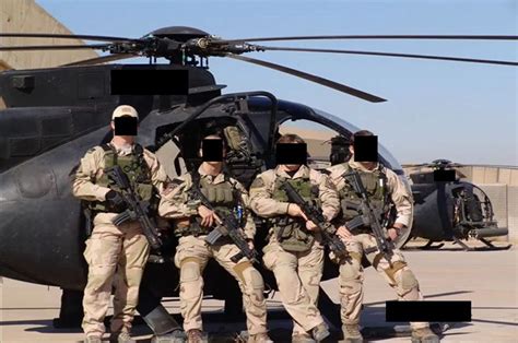 four men in uniform standing next to a helicopter