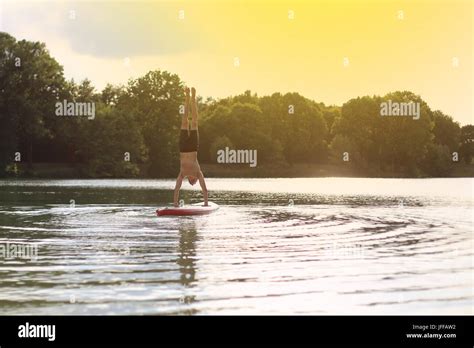 SUP yoga at stand up paddling handstand Stock Photo - Alamy