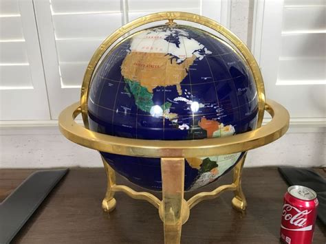 a blue and gold globe sitting on top of a wooden table next to a can of coke