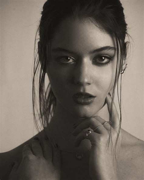 a black and white photo of a woman's face with her hands under her chin