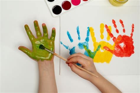 Premium Photo | The child draws his hand with green paint and a brush ...