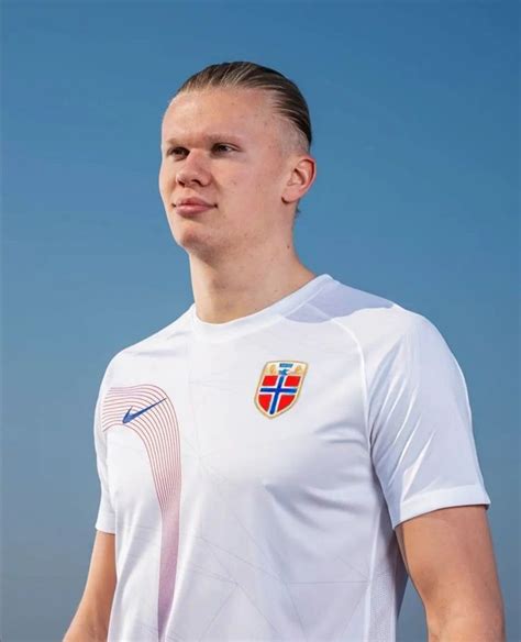 a man standing in front of a blue sky wearing a white shirt with the flag of norway on it