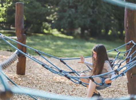 Caucasian Girl Sits Half-side on a Blue Rope Swing in a Park on a Playground Stock Image - Image ...