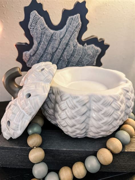 a white bowl sitting on top of a wooden table next to a beaded necklace