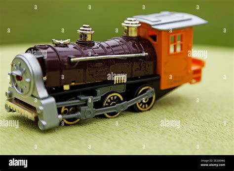 an orange and black toy train on a green background Stock Photo - Alamy