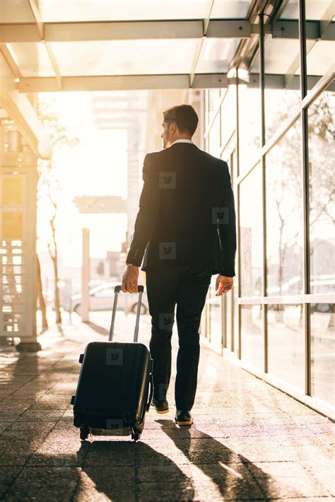 Young businessman walking with suitcase outside airport building stock photo (128872 ...