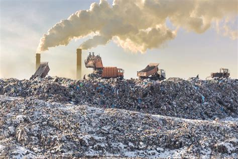 Dump trucks unloading garbage over vast landfill. Smoking industrial ...