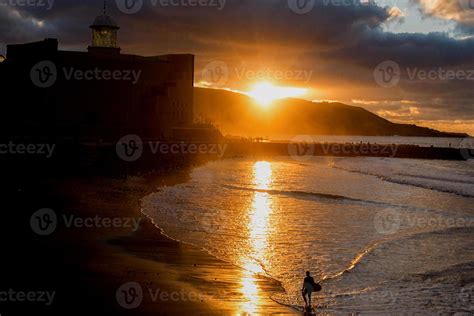 surfing on the beach at sunset 4408876 Stock Photo at Vecteezy