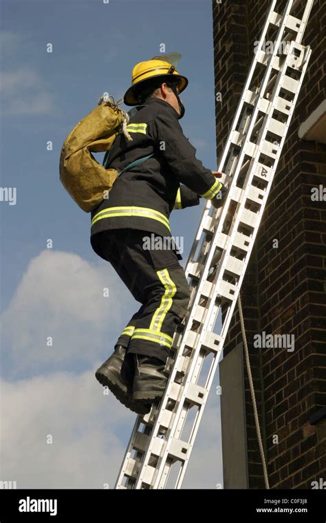 ECFRS Fire Brigade Fireman climbs a ladder Stock Photo - Alamy