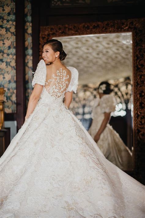 a woman standing in front of a mirror wearing a wedding dress