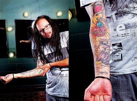 a man with long hair and tattoos on his arm pointing at something in the mirror