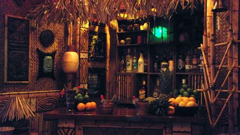 a bar with lots of bottles and fruit on it's counter top next to bamboo shelves