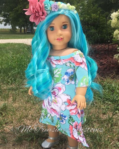 a doll with blue hair and flowers on her head is standing in the grass wearing sandals