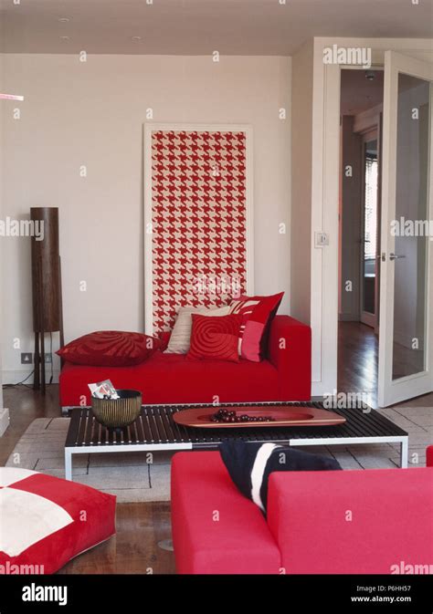 Patterned red cushions on bright red sofa in front of large red+white hounds-tooth picture in ...