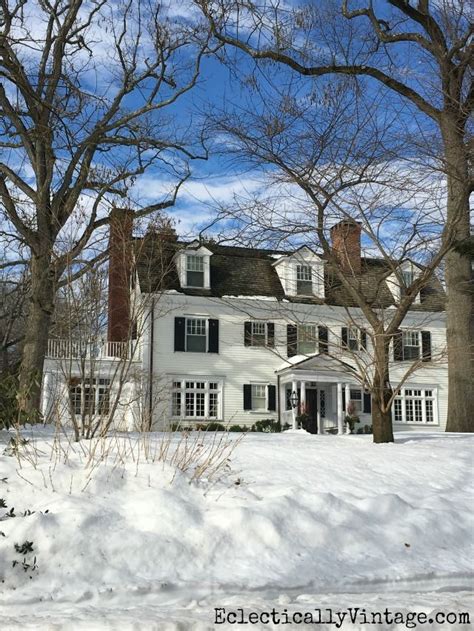 a large white house sitting in the middle of a snow covered field next ...