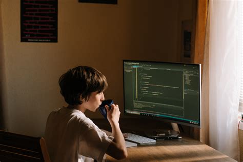 Boy in White T-shirt Sitting on Chair in Front of Computer · Free Stock Photo