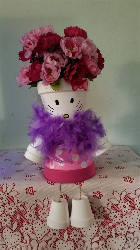 a hello kitty planter with flowers in it on a doily covered tablecloth