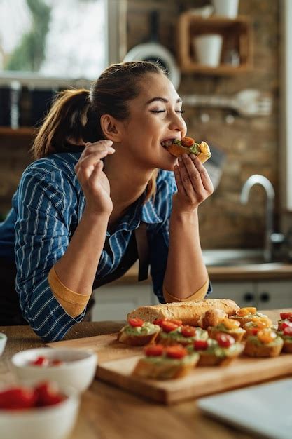 Free Photo | Young woman enjoying in taste on healthy bruschetta with her eyes closed in the kitchen