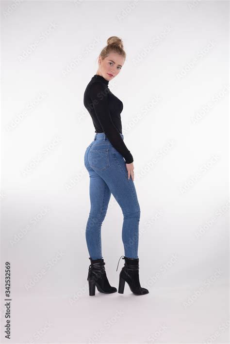 Sexy teen girl in tight jeans and sweater, looking back over shoulder ...