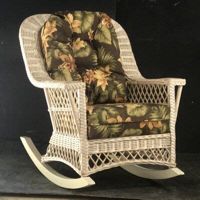 a white wicker rocking chair with tropical print fabric on the seat and back cushions