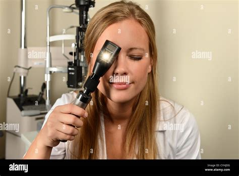 Female eye doctor looking through ophthalmoscope in examination room Stock Photo - Alamy