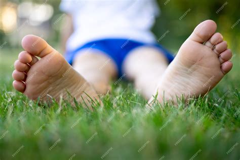 Premium Photo | Barefoot feet close-up, a child sitting on the grass in ...