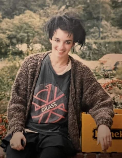 a woman sitting on top of a brick wall next to a yellow box filled with flowers