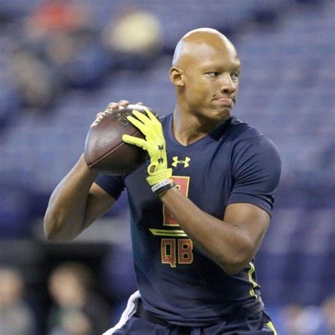 a man holding a football in his right hand and wearing yellow gloves on ...