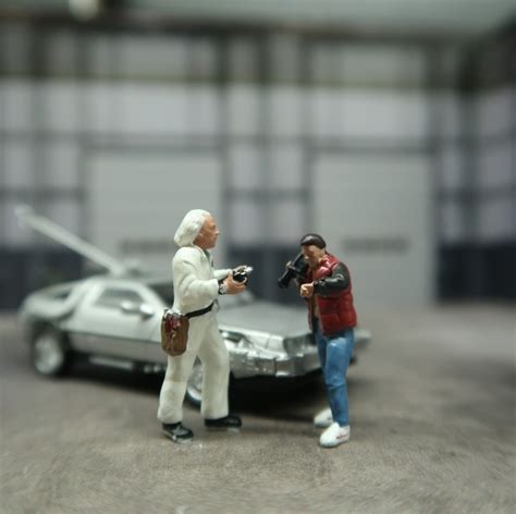 two figurines are standing in front of a toy car and one is holding a ...