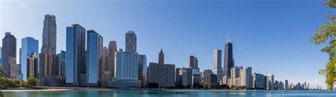 Panoramic image of the Chicago skyline with skyscrapers by the water with blue sky and no clouds ...