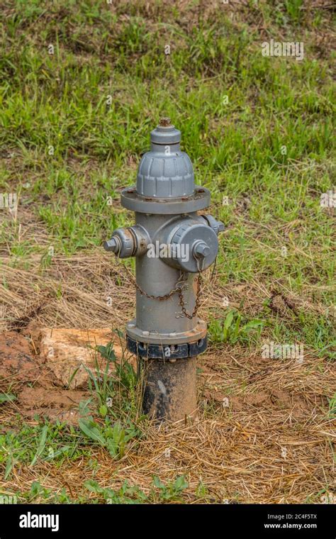 A repaired gray fire hydrant above ground in dirt and grass outdoors ready to fight fires Stock ...