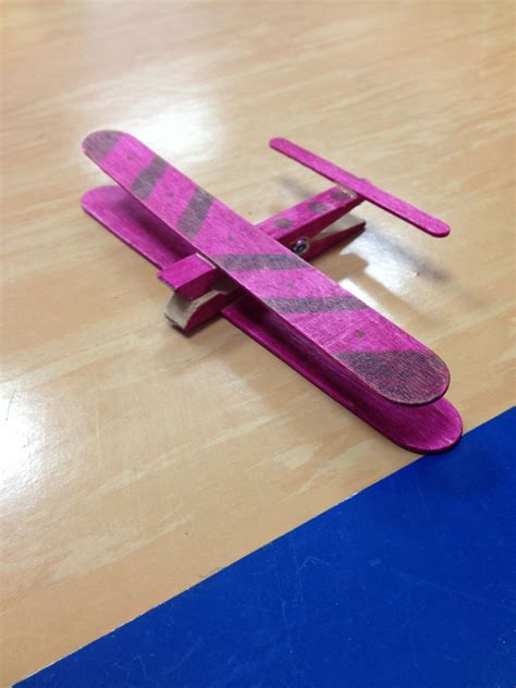 a pink toy airplane sitting on top of a wooden table next to a blue strip