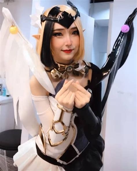 a woman dressed up as an angel holding a large object in one hand and pointing at the camera