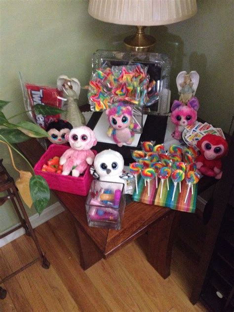 a table topped with lots of stuffed animals on top of a wooden table next to a lamp