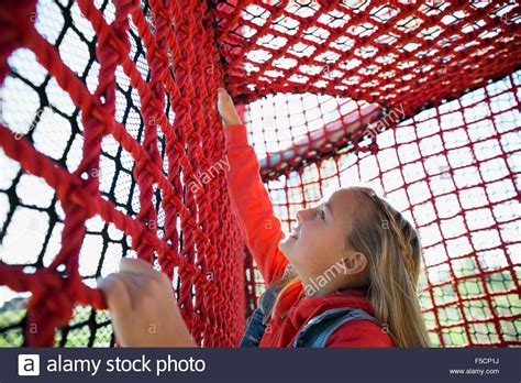 Girl climbing rope net at playground Stock Photo - Alamy