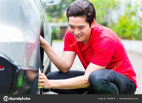 Asian man cleaning car rims — Stock Photo © Kzenon #139246616