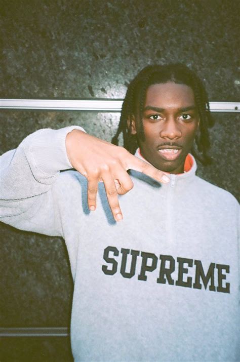 a man with dreadlocks pointing at the camera while wearing a supreme hoodie