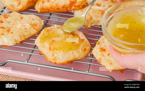 Topping biscuits with mix of melted butter and garlic seasoning. Fresh baked cheese biscuits ...