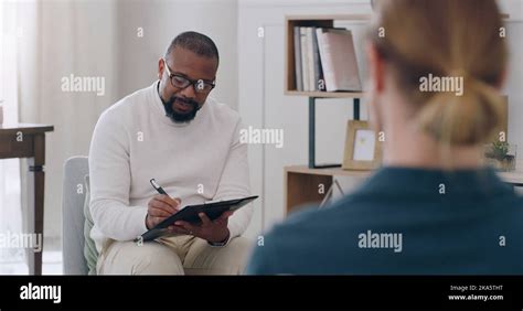 Black man, psychology and writing note with woman patient in counseling appointment for help ...