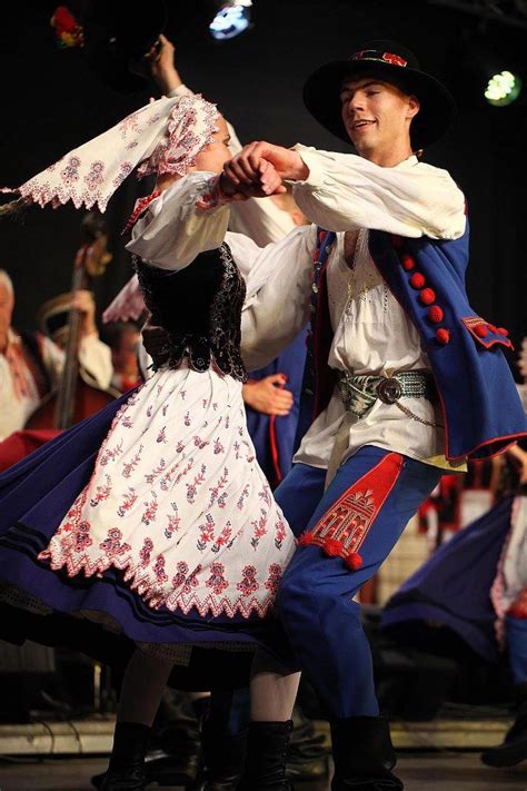 two people dressed in folk clothing dancing on stage