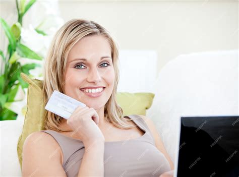 Premium Photo | Attractive woman lying on a sofa with a laptop holding a card