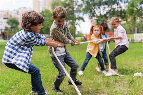 adorable happy kids playing tug of war in park - Stock Photo - Dissolve